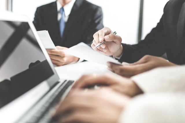 Businessmen reviewing contract pen laptop