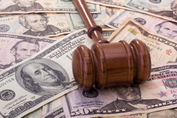 An image of a wooden gavel on top of 100, 5, and 20 dollar bills.