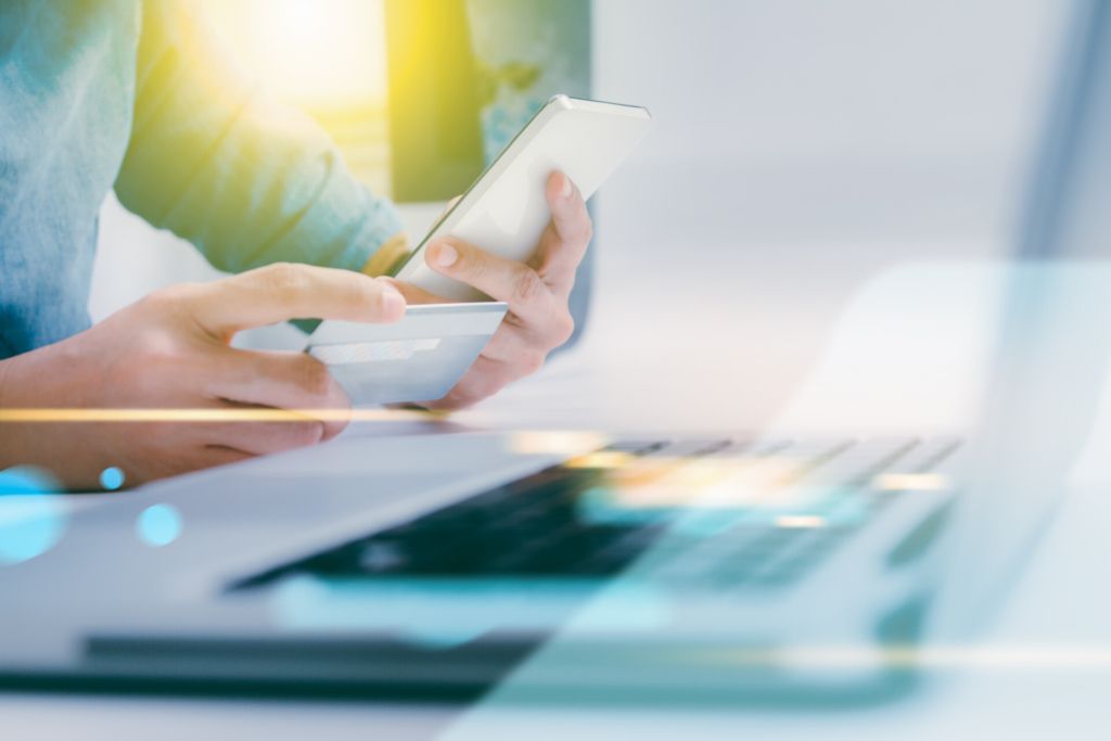 image of a womans hand holding a debit card and looking at a phone screen.