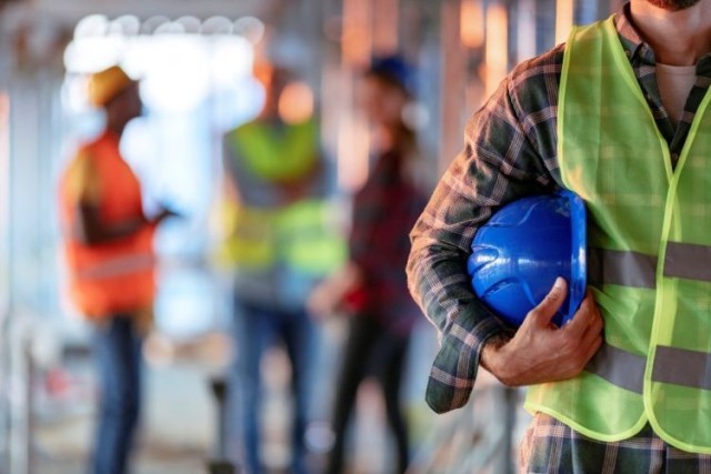 Construction workers and a man holding blue helmet close up