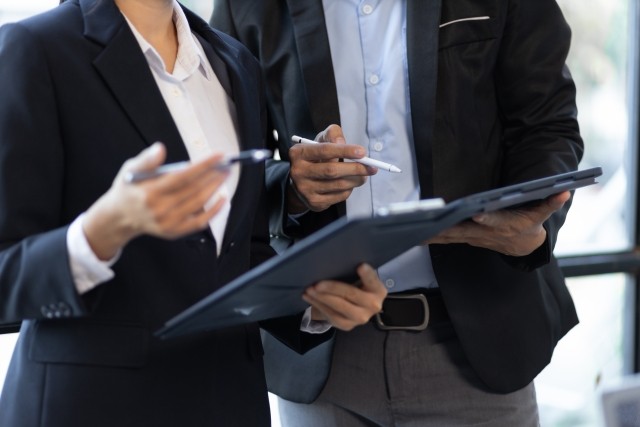 two businesspeople looking at documents while standing