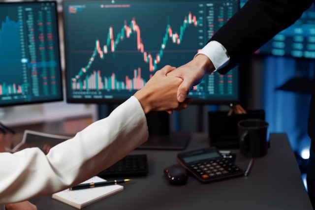 Handshake with stock screens in background