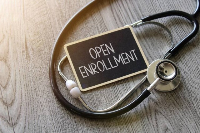 Open Enrollment written on chalkboard with stethoscope on desktop.