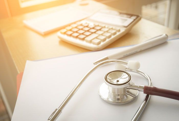 Stethoscope on desk with paperwork and calculator