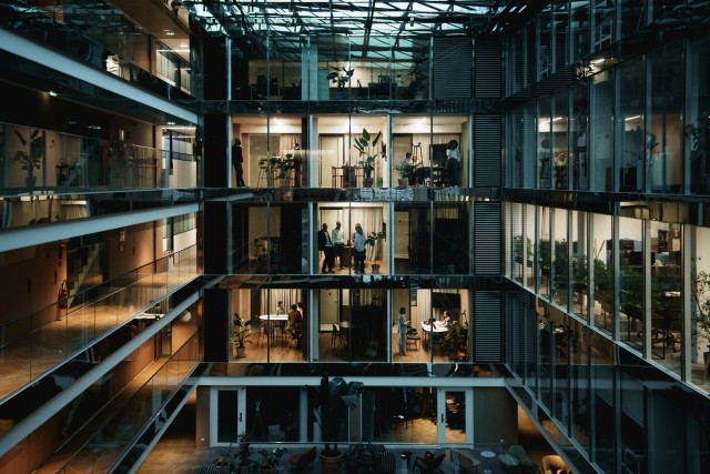 dark office building lit up with workspaces filled with people