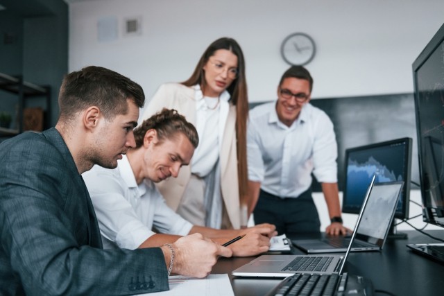 businesspeople looking over paperwork and desktop. Mixed emotions