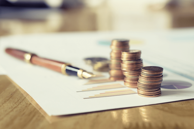 ink pen next to coins and financial documents