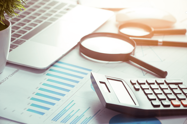 Magnifying Glass and a Calculator resting on a desk