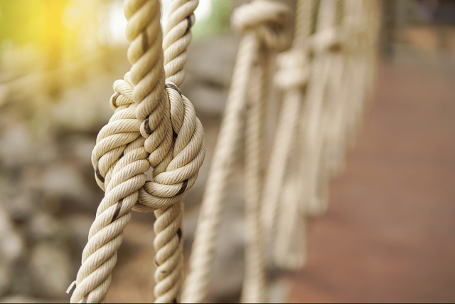 Rope knots on a bridge while the sun is shining outside.